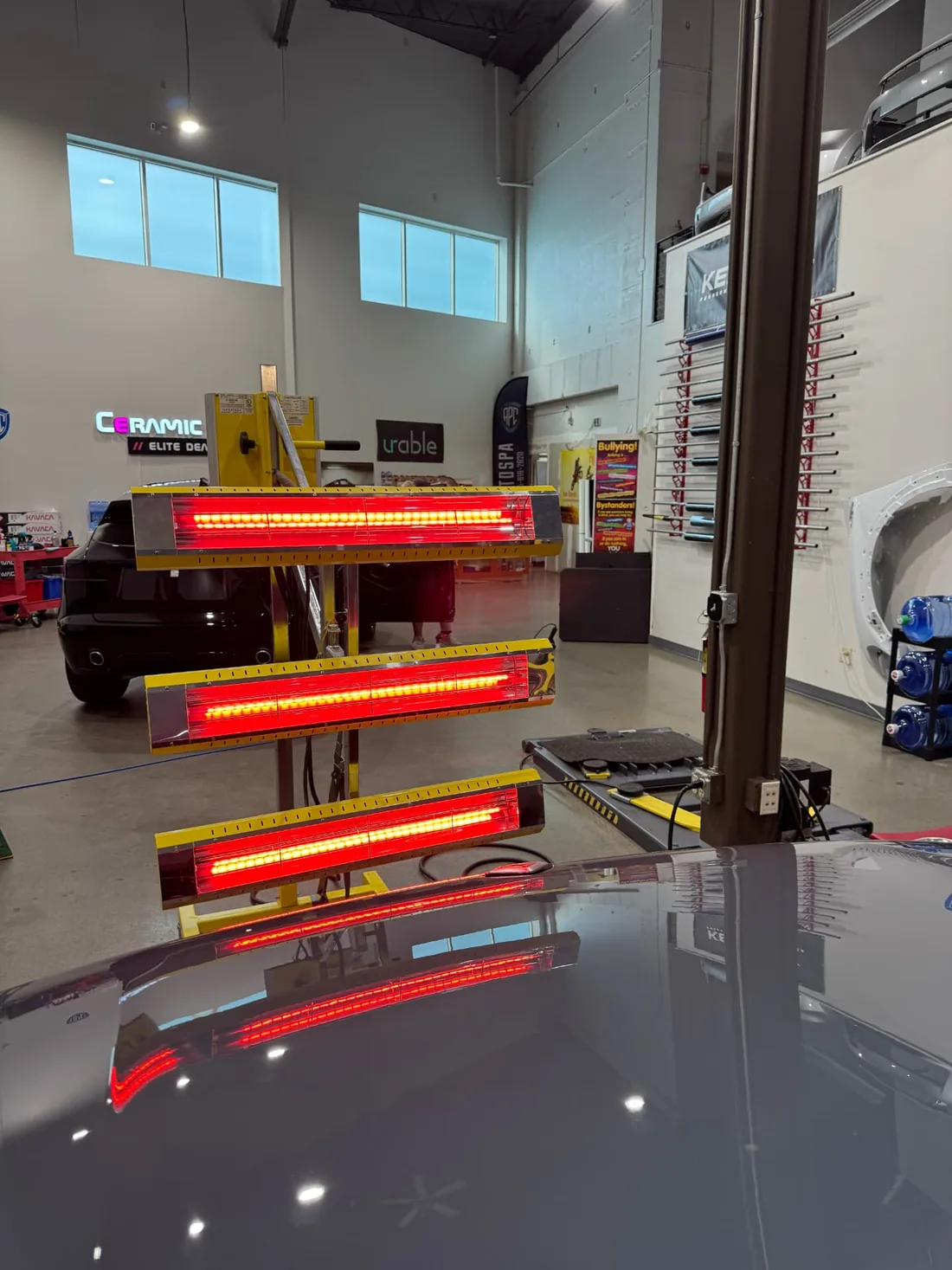 Infrared lamps curing ceramic coating over a vehicle panel at APC Auto Spa