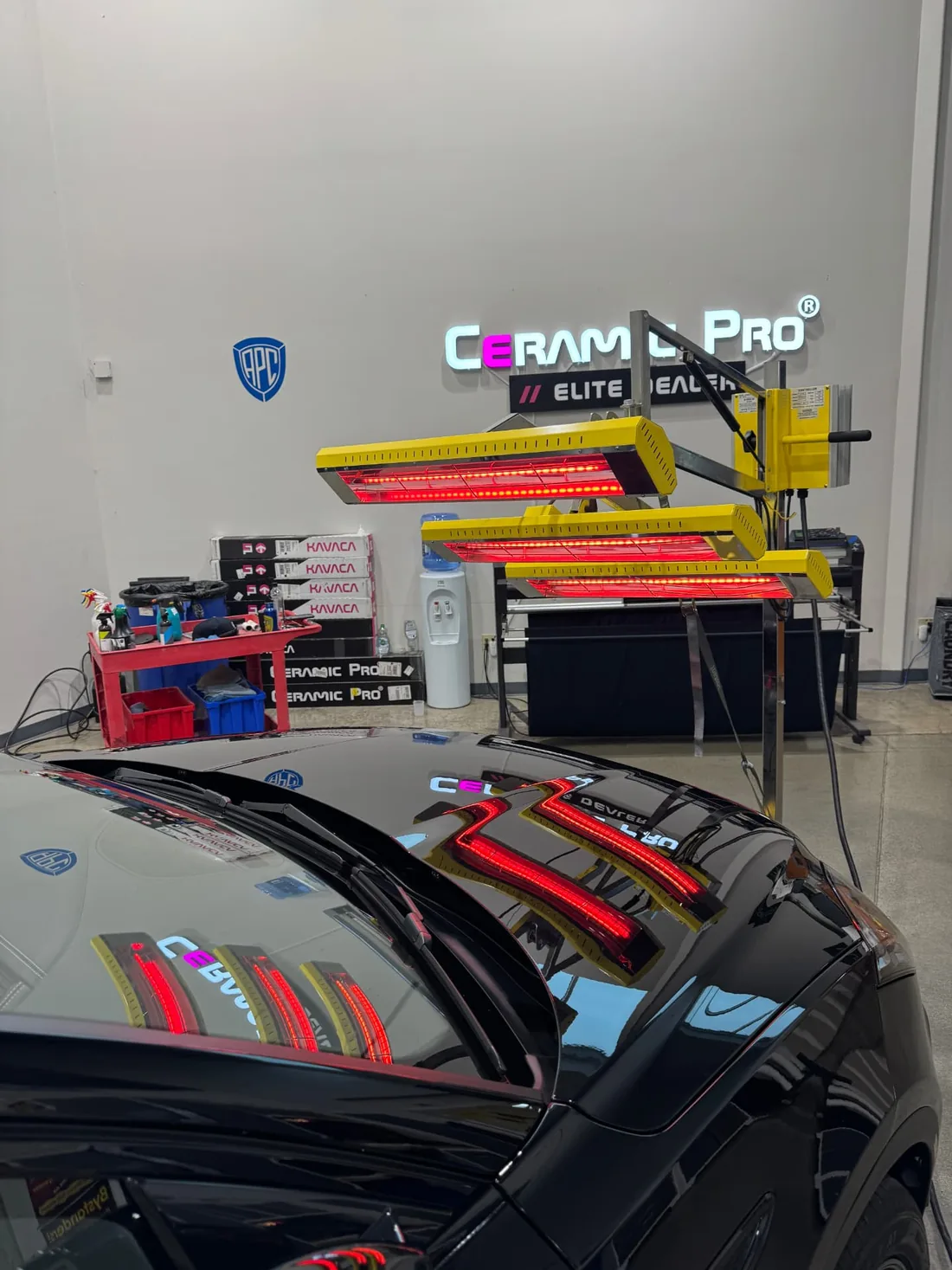 Infrared curing lamps positioned over a freshly coated black vehicle