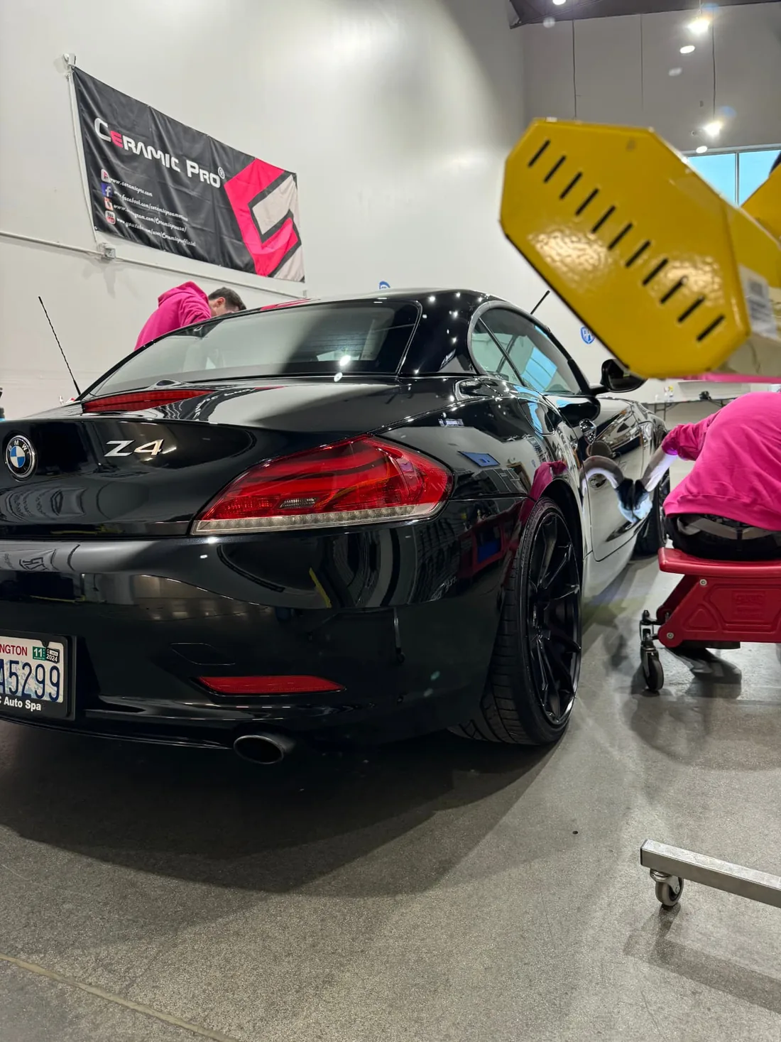 APC Auto Spa technicians working together on a black BMW in the Monroe shop